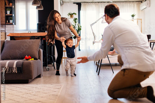 Billede på lærred Young married couple teaching their son to learn the first baby steps in their h