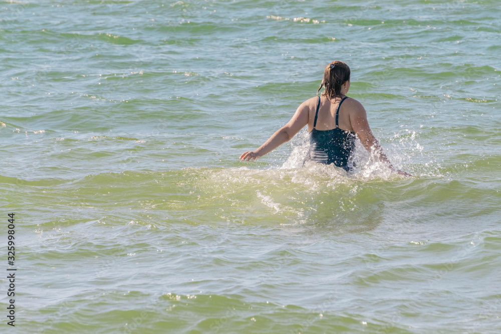 Woman going into waving sea and making splashes of water Woman going into waving sea and making splashes of water