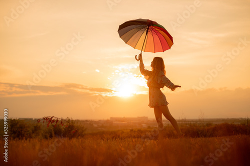 Young woman with umbrella dancing during sunset
