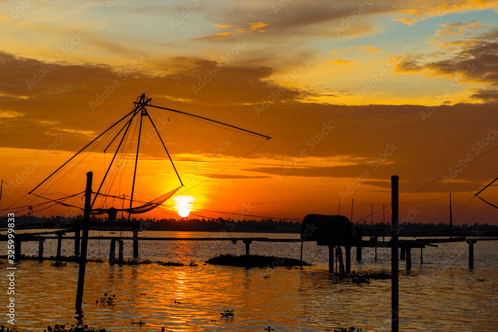 Warm sunset on the backwaters of Kumablangi, Cochin, India, with fishing nets on the foreground.