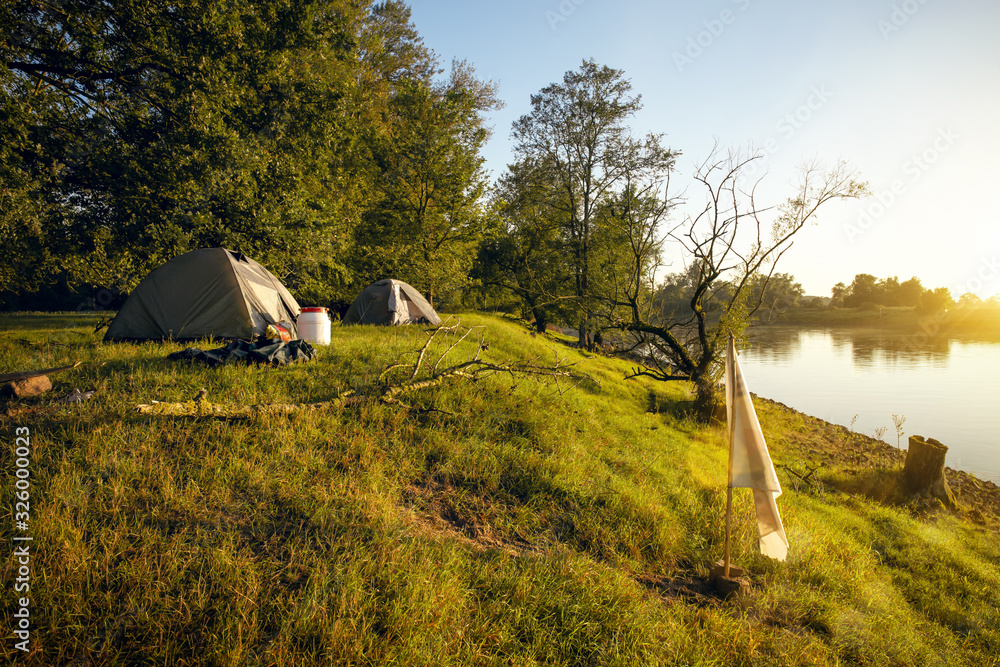 Two tents next to a river at sunrise