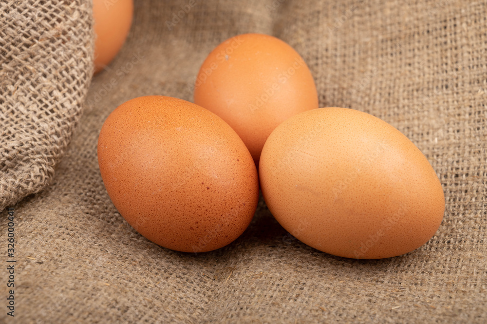 Chicken eggs on a background of rough homespun fabric. Homemade preparations, rustic treats. Close up. Chicken eggs on a background of rough homespun fabric. Homemade preparations, rustic treats. Close up.
