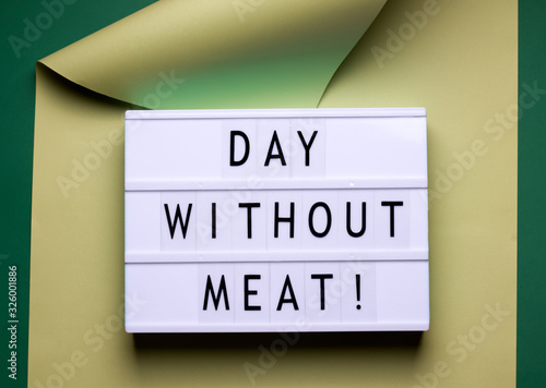 Fototapeta Naklejka Na Ścianę i Meble -  on a green background there is a lightbox with the text wrapped in paper. International Day Without Meat concept