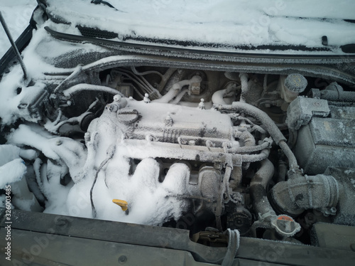 Car engine covered by snow and ice.