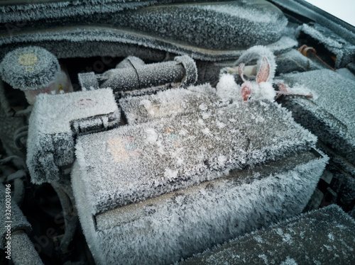 Car battery covered in snow and ice. Large pieces of ice covered the surface and contacts of the battery.