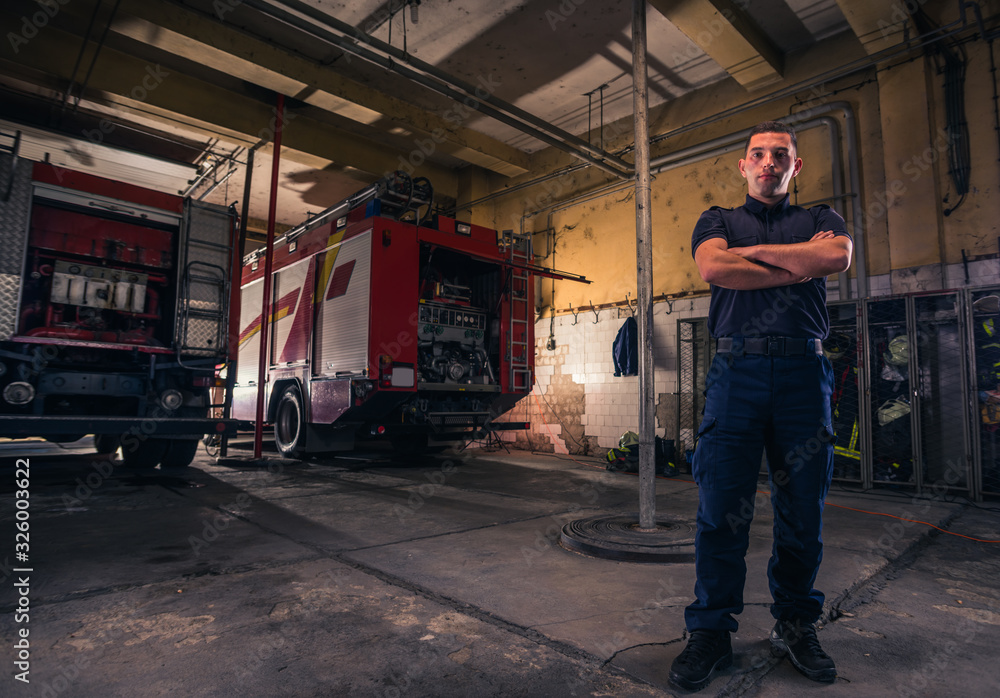 Portrait of confident young fireman standing inside the fire departmant