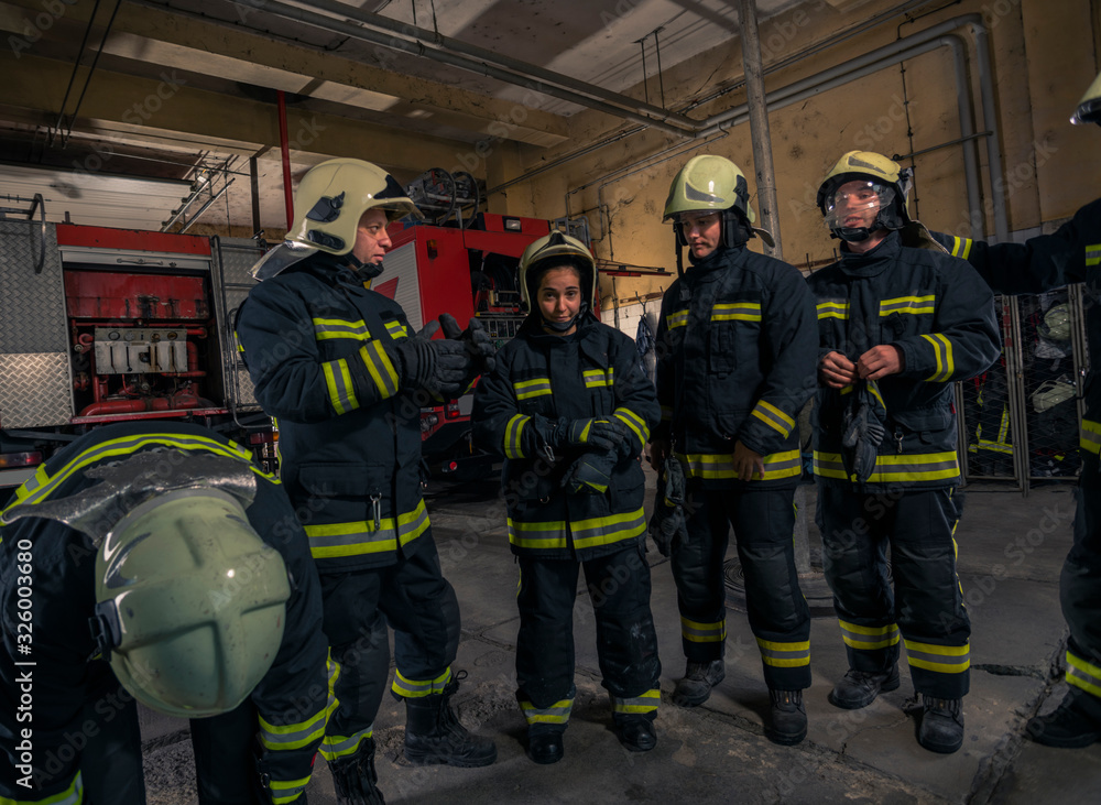 Fototapeta premium Firemen preparing for emergency service. Firefighters putting on gloves.