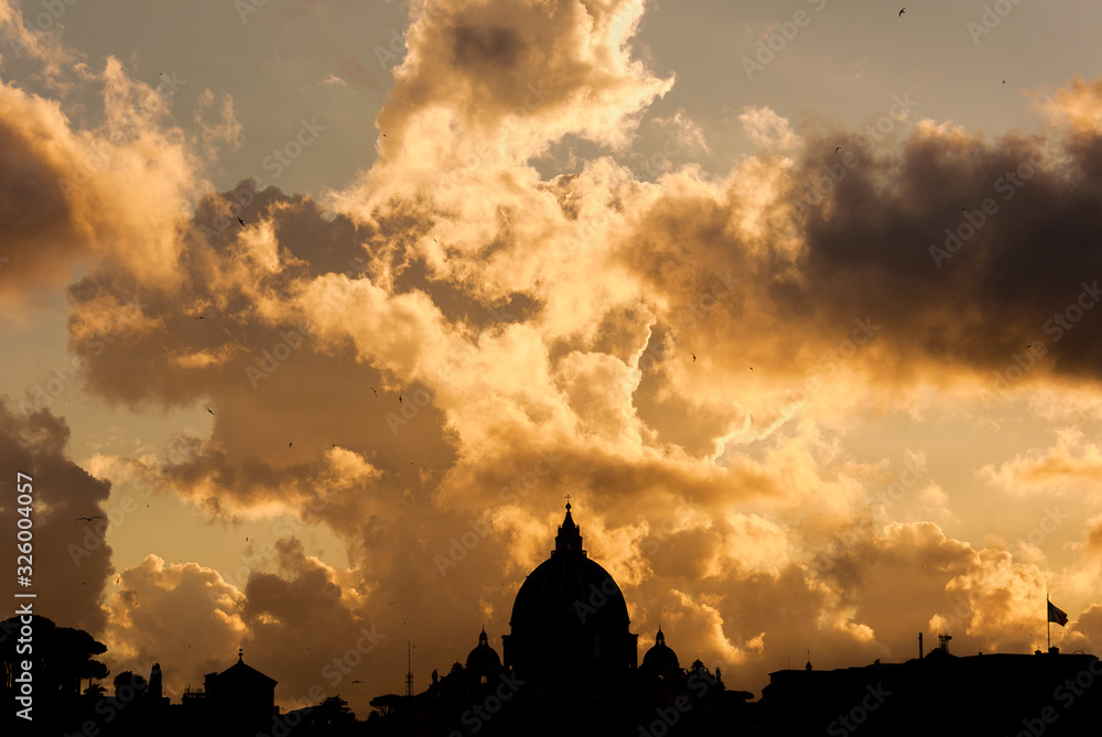 Beautiful sunset sky and clouds over Rome historic center skyline with the famous and iconic St Peter's Dome