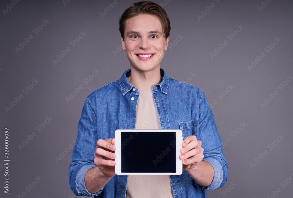 Portrait of an attractive guy in a denim shirt with a tablet in his hand. Portrait of an attractive guy in a denim shirt with a tablet in his hand.