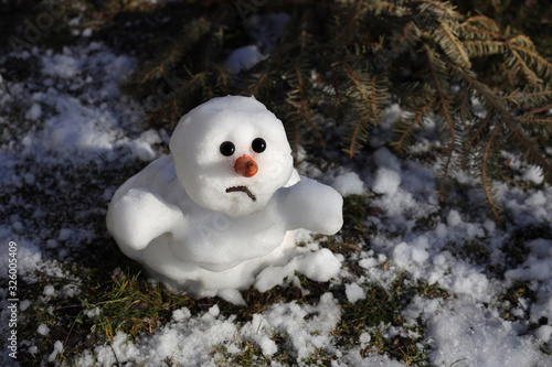 Snowman is melting in the sun. Thaw, warm winter, early spring, global warming, climate change. Spring background.