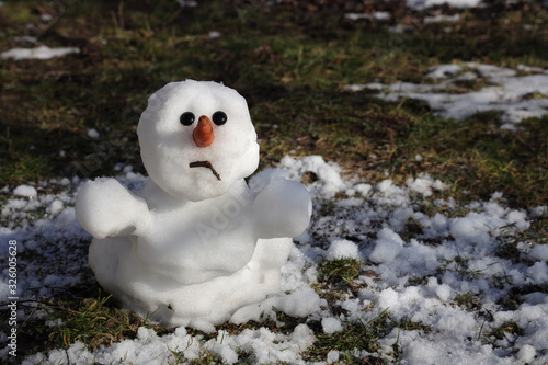 Snowman is melting in the sun. Thaw, warm winter, early spring, global warming, climate change. Spring background. photo