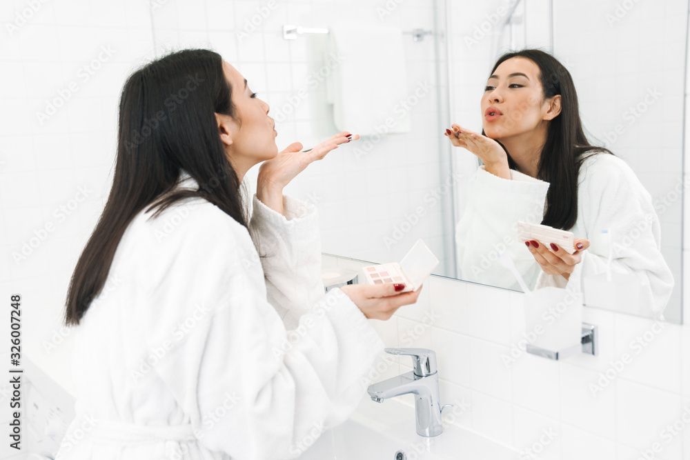 Woman indoors at home in bathroom apply makeup Woman indoors at home in bathroom apply makeup
