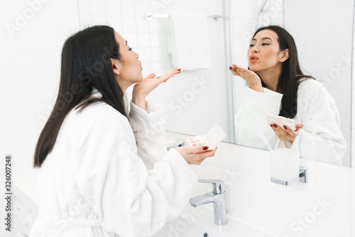 Woman indoors at home in bathroom apply makeup