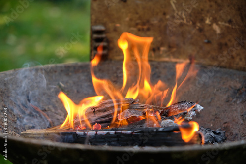 Flames coming out of a heap of cardboard, paper, wood and twigs in a barbecue in the garden.