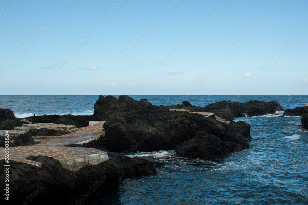 Natural natural baths on the beach. Natural pools surrounded by black volcanic rock.