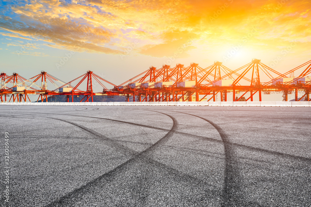 Empty race track and industrial container freight port at beautiful sunset in Shanghai.