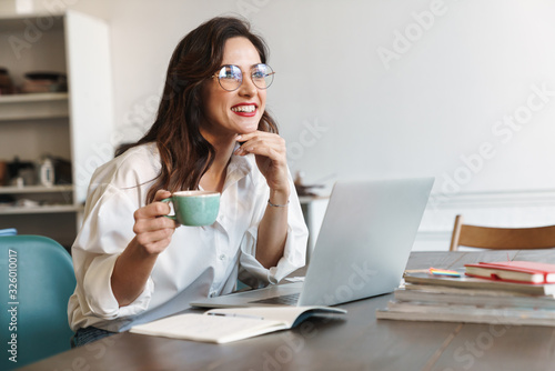 Happy positive young woman using laptop computer.