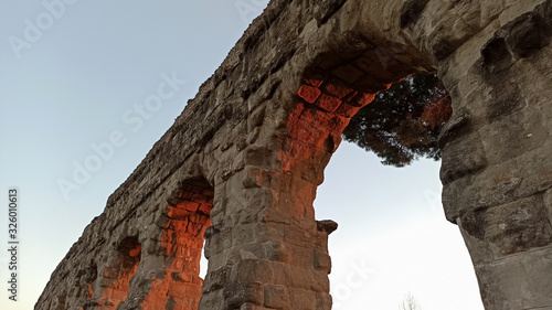 Rovine di acquedotto romano al tramonto fotografate dal basso  photo