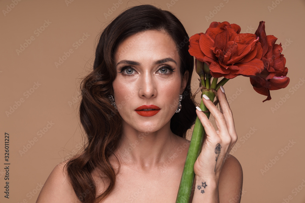 Beauty portrait of brunette adult half-naked woman holding red flowers