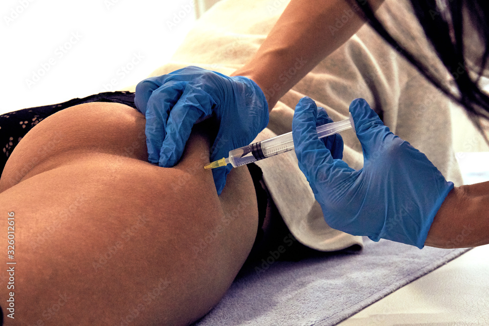 Woman lying on bed and getting Botox injection.