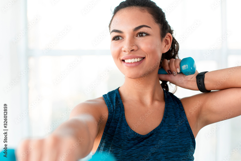 Charming Latin woman working out with dumbbells in gym Charming Latin woman working out with dumbbells in gym