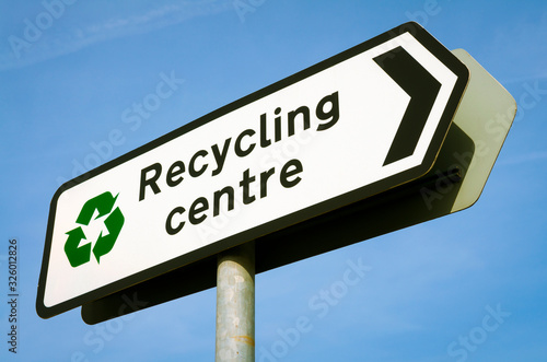 Sign pointing the way to the Recycling Centre standing in bright blue sky