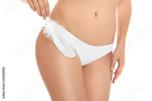 Woman with feather showing smooth skin on white background, closeup. Brazilian bikini epilation