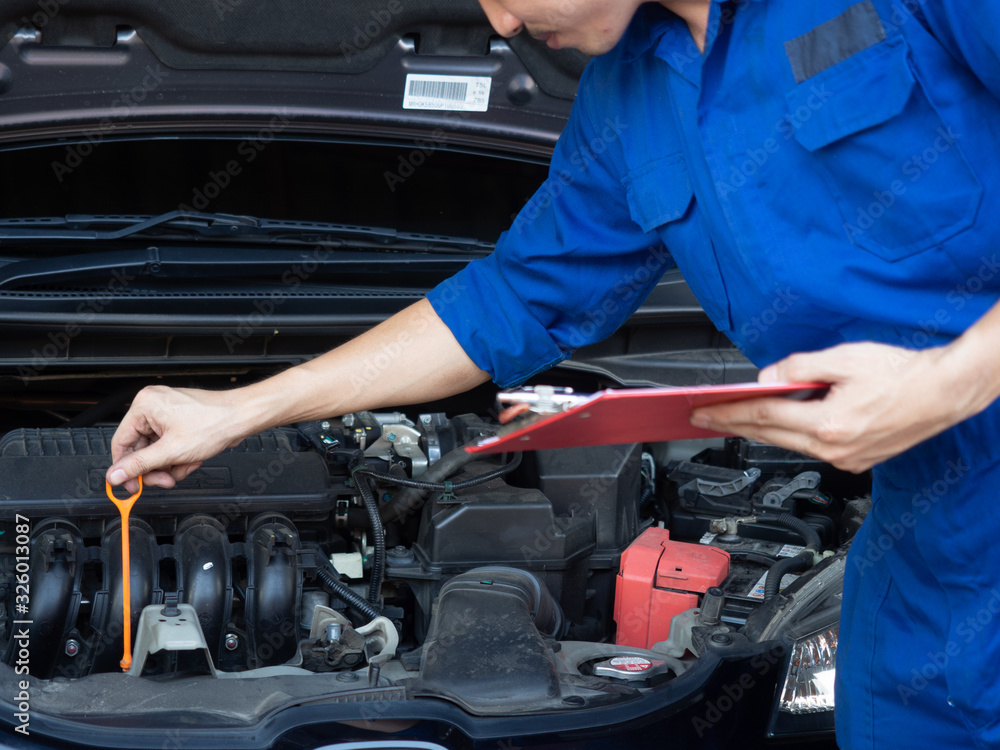 Auto mechanic working in garage. Repair service.asia man checking the oil level