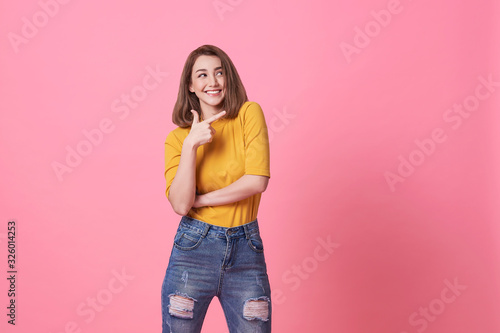 Beautiful healthy young woman smiling with his finger pointing and looking at on light pink banner background with copy space.