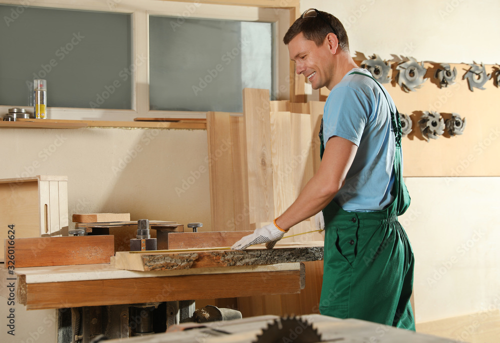Professional carpenter measuring wooden board in workshop Professional carpenter measuring wooden board in workshop