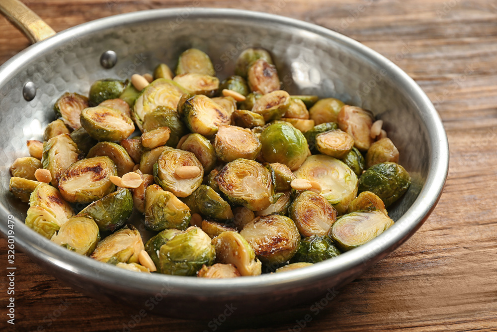 Delicious roasted brussels sprouts with peanuts on wooden table, closeup