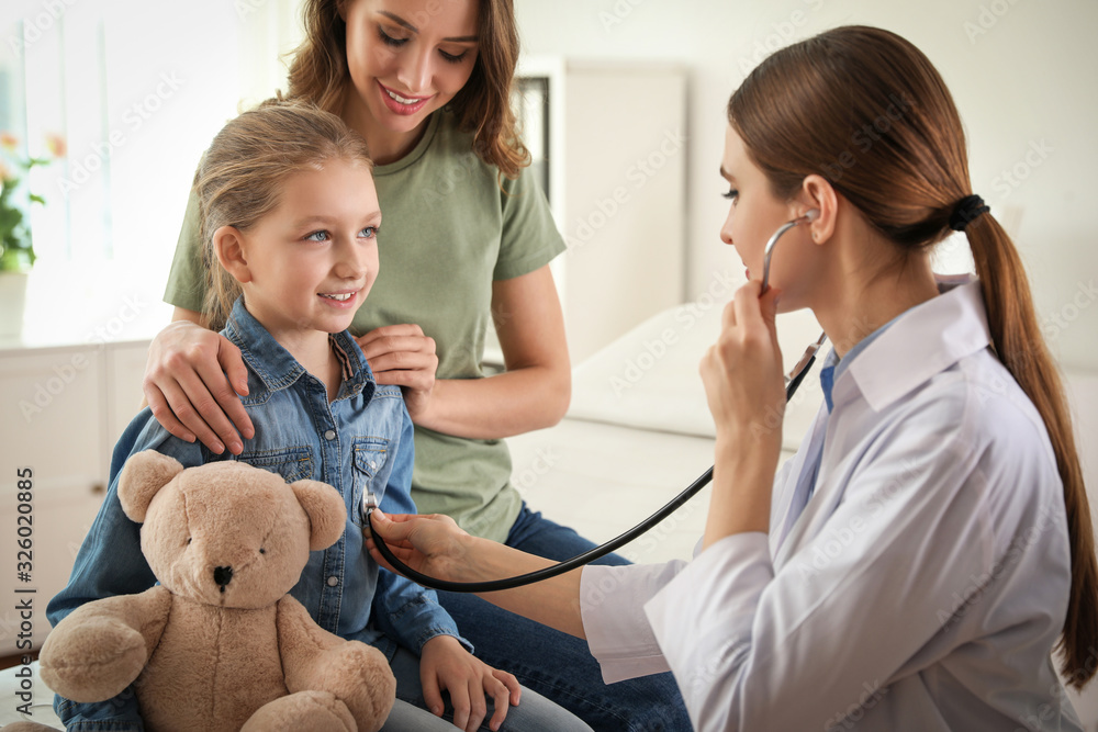Mother and daughter visiting pediatrician. Doctor examining little patient with stethoscope in hospital Mother and daughter visiting pediatrician. Doctor examining little patient with stethoscope in hospital