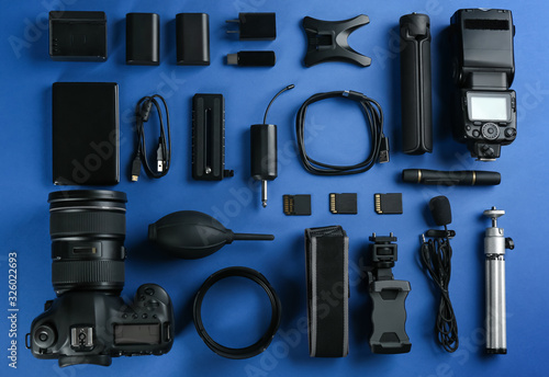 Flat lay composition with camera and video production equipment on blue background