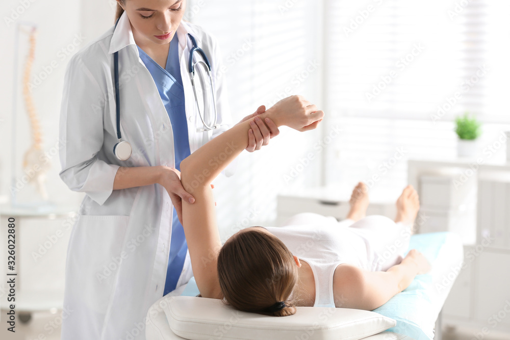Obraz premium Female orthopedist examining patient's arm in clinic