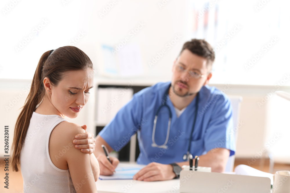 Male orthopedist examining patient with injured arm in clinic Male orthopedist examining patient with injured arm in clinic