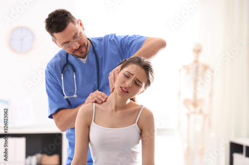 Male orthopedist examining patient's neck in clinic