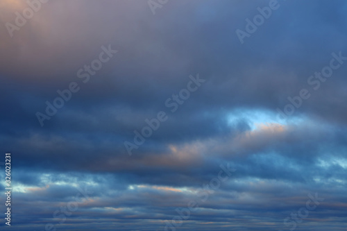 Low cloud cover. Dense dark clouds lit by the sun with gleams of the blue sky as expressive dramatic backdrop. © Na-um