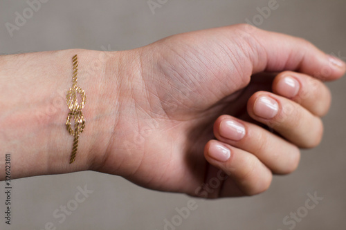 Canvas Print hand of a young woman wih gold sailors knot temporary tattoo on her wrist