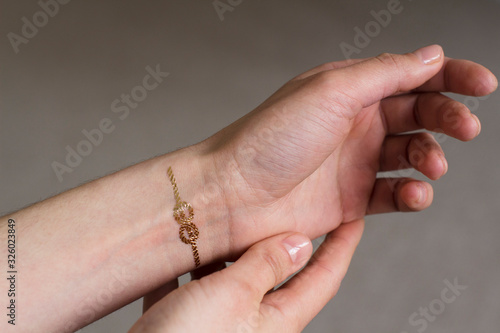 hand of a young woman wih gold sailors knot temporary tattoo on her wrist