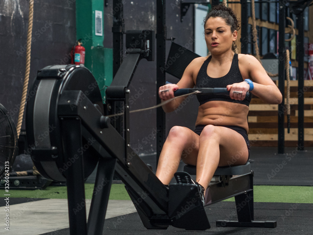 Fototapeta premium Woman training in the gym with the rowing machine