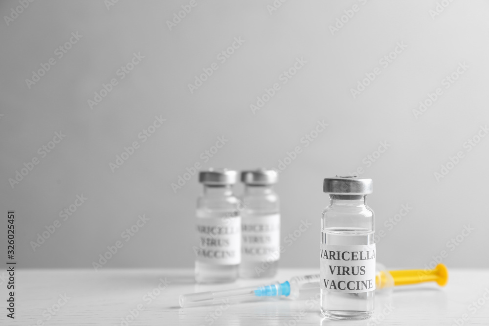 Chickenpox vaccine and syringe on white wooden table, space for text. Varicella virus prevention Chickenpox vaccine and syringe on white wooden table, space for text. Varicella virus prevention