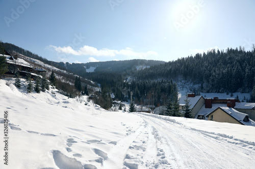 Fototapeta Naklejka Na Ścianę i Meble -  Beautiful mountain landscape with snowy hills and houses on sunny day in winter