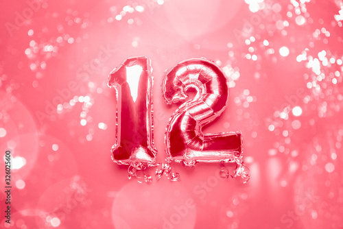 Silver Number Balloons 12 with bokeh lights. Holiday Party Decoration or postcard concept with top view  toned in pink