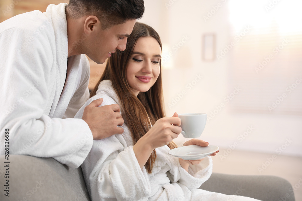 Man in bathrobe hugging his girlfriend with coffee at home Man in bathrobe hugging his girlfriend with coffee at home