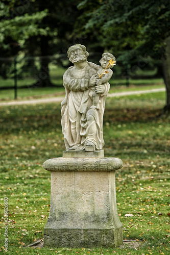 Statue of old man hodling child on the pedestal in park