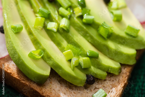 close up of sandwich with avocado and green onion