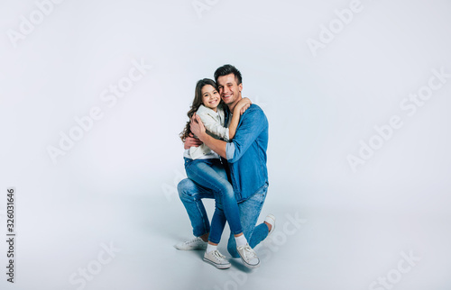 My future. Full-length photo of a beautiful little child and with long hair and her happy dad, who is standing on his knee, while holding her in his arms.