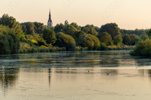Φωτογραφία Église Saint-Martin de Bousbecq sous le soleil du soir le long de la Lys à la frontière française à Wervik