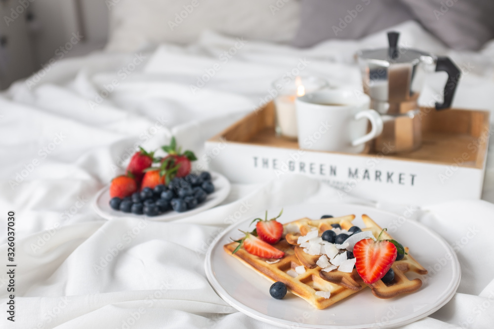 Beautiful breakfast in bed: Viennese Belgian waffles decorated with berries, a plate with strawberries and blueberries Beautiful breakfast in bed: Viennese Belgian waffles decorated with berries, a plate with strawberries and blueberries