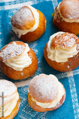 Fresh semla (vastlakukkel in Estonia) on the retro cotton tablecloth. Traditional sweet bun with whipped cream made in Scandinavic and Baltic countries for Shrove Tuesday or related days